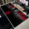 A black mouse pad featuring a stylized white and red design inspired by the Berserk anime, placed on a desk next to a keyboar