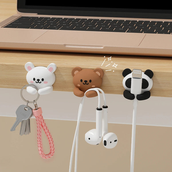 Un juego de organizadores de cables para escritorio con cabezas de oso y panda y cordones blancos para gestionar cables.