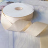 Roll of matte finish satin ribbon in a light beige color displayed on a white surface.