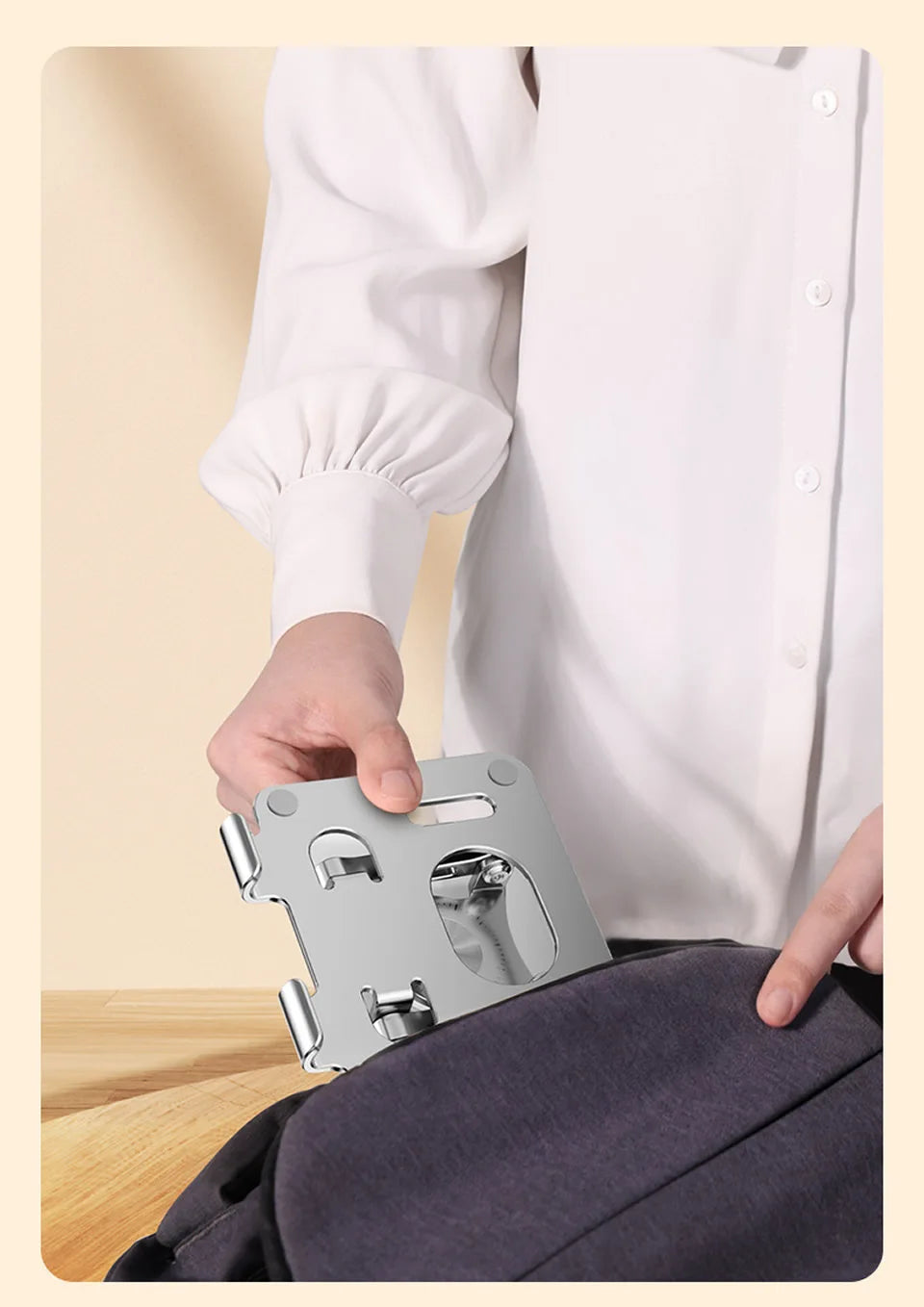 A hand holds a silver 360° rotating tablet stand against a dark gray fabric.