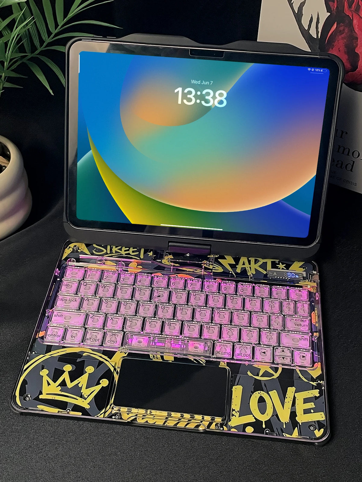 A purple keyboard case with an RGB backlit trackpad is shown next to an iPad displaying a time.