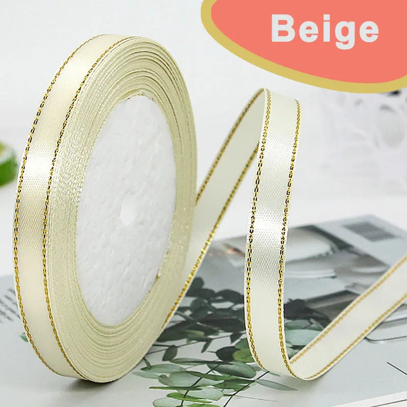 Roll of beige satin ribbon with gold edge and a matching ribbon strip