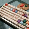 A close-up view of a keyboard with retro AI illustrator PBT keycaps in cherry profile and various colors, resting on a wooden