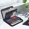 A black multi-compartment fireproof organizer file folder is open, displaying various documents and cards on a white surface.
