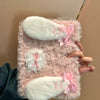 A pink fluffy rabbit plush case with white ears is held by a hand against a light background.