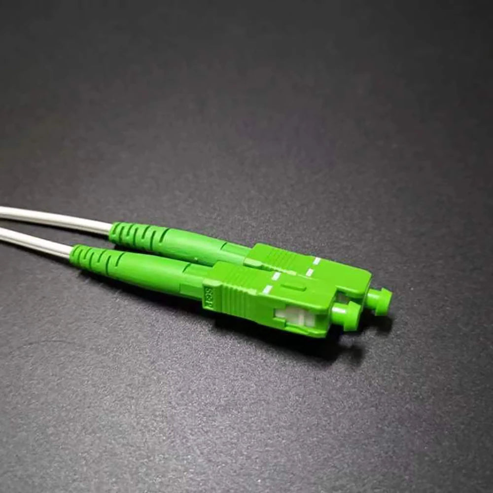 A close-up of a green single-mode fiber optic cable connector with a white jacket and silver tip.