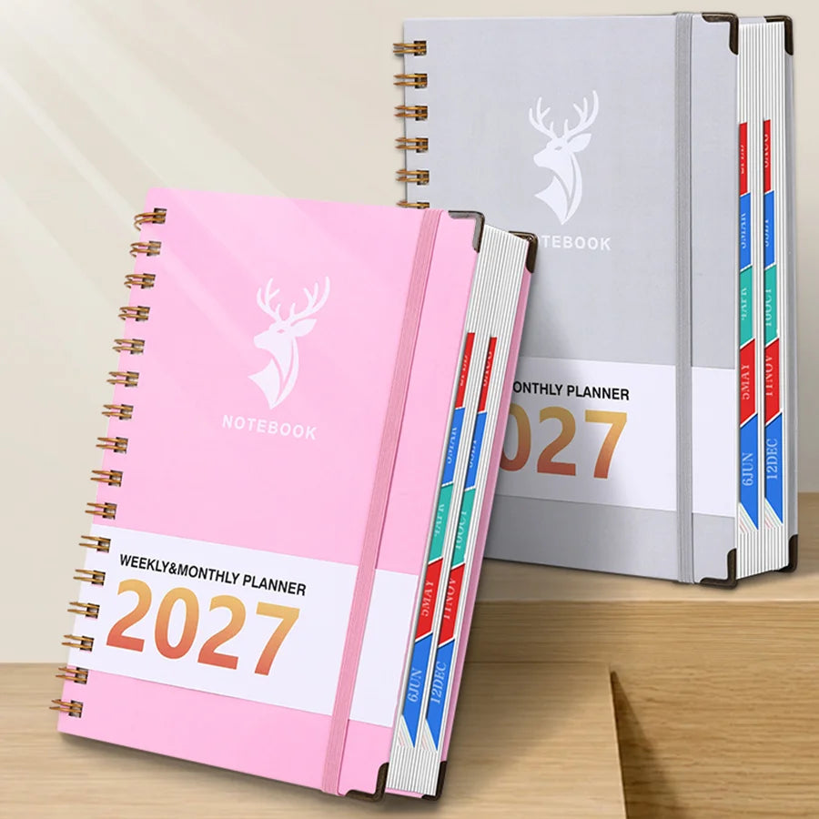Pink spiral-bound weekly and monthly planner for 2027 with a deer design next to a gray notebook.