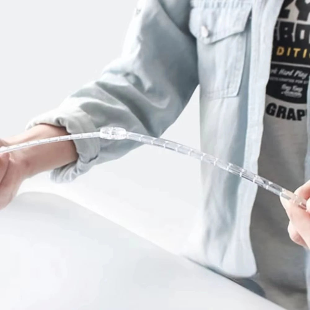 A hand is holding a clear, flexible ruler or measuring tape against a light background.