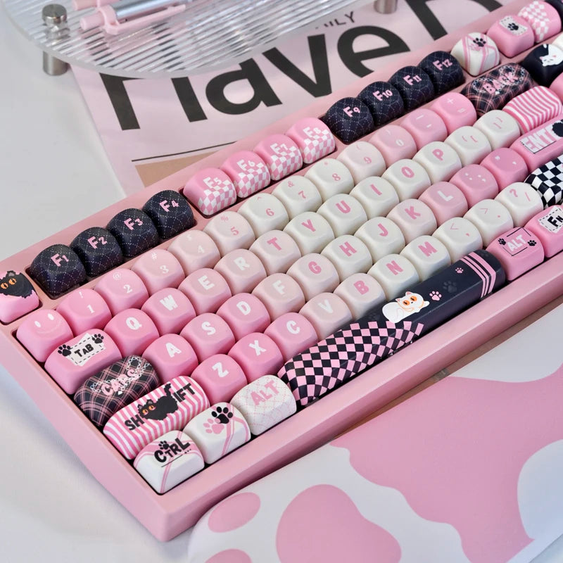 A pink PBT keycap set featuring a cat print design is displayed on a keyboard tray.
