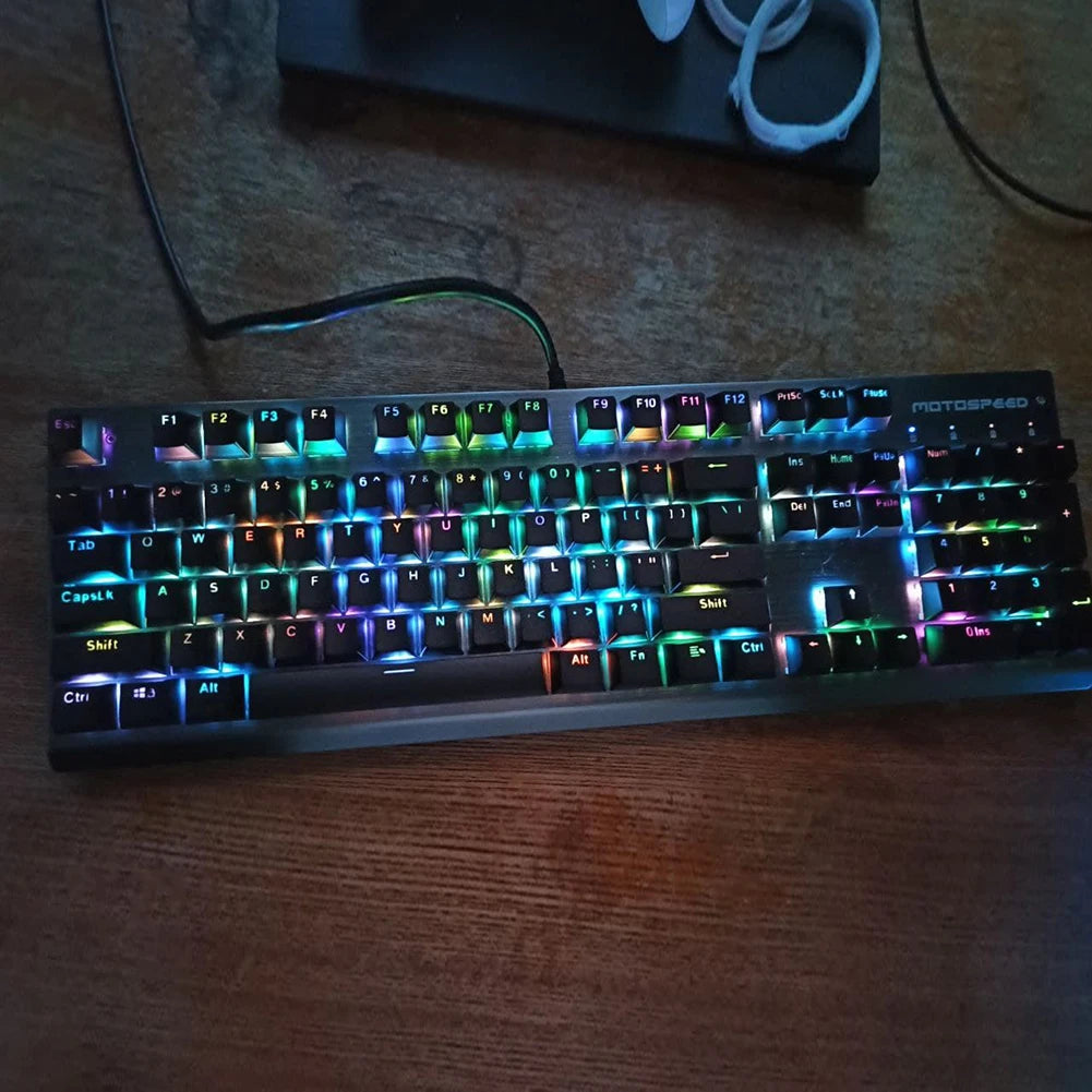 A close-up shot of a black mechanical keyboard with colorful RGB backlighting resting on a wooden surface.