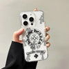 A hand holds a clear acrylic phone case featuring a black and white design of a horseshoe, heart, and floral elements.