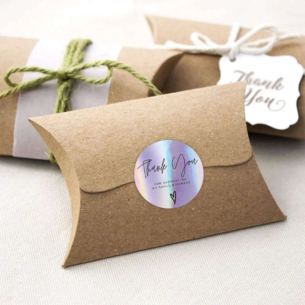 A brown kraft paper thank you card with a circular iridescent sticker that reads Thank You for supporting my small business