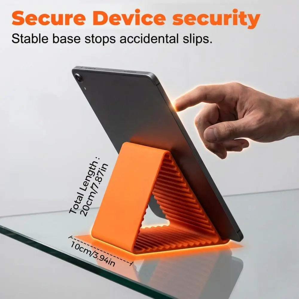 A hand places a flexible silicone orange phone stand on a glass surface to secure a device.