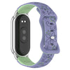 A purple silicone smart watch band with green engraved flowers and a silver casing.