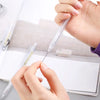 A hand is using a syringe to apply ink or liquid to the tip of a minimalist mechanical pencil.