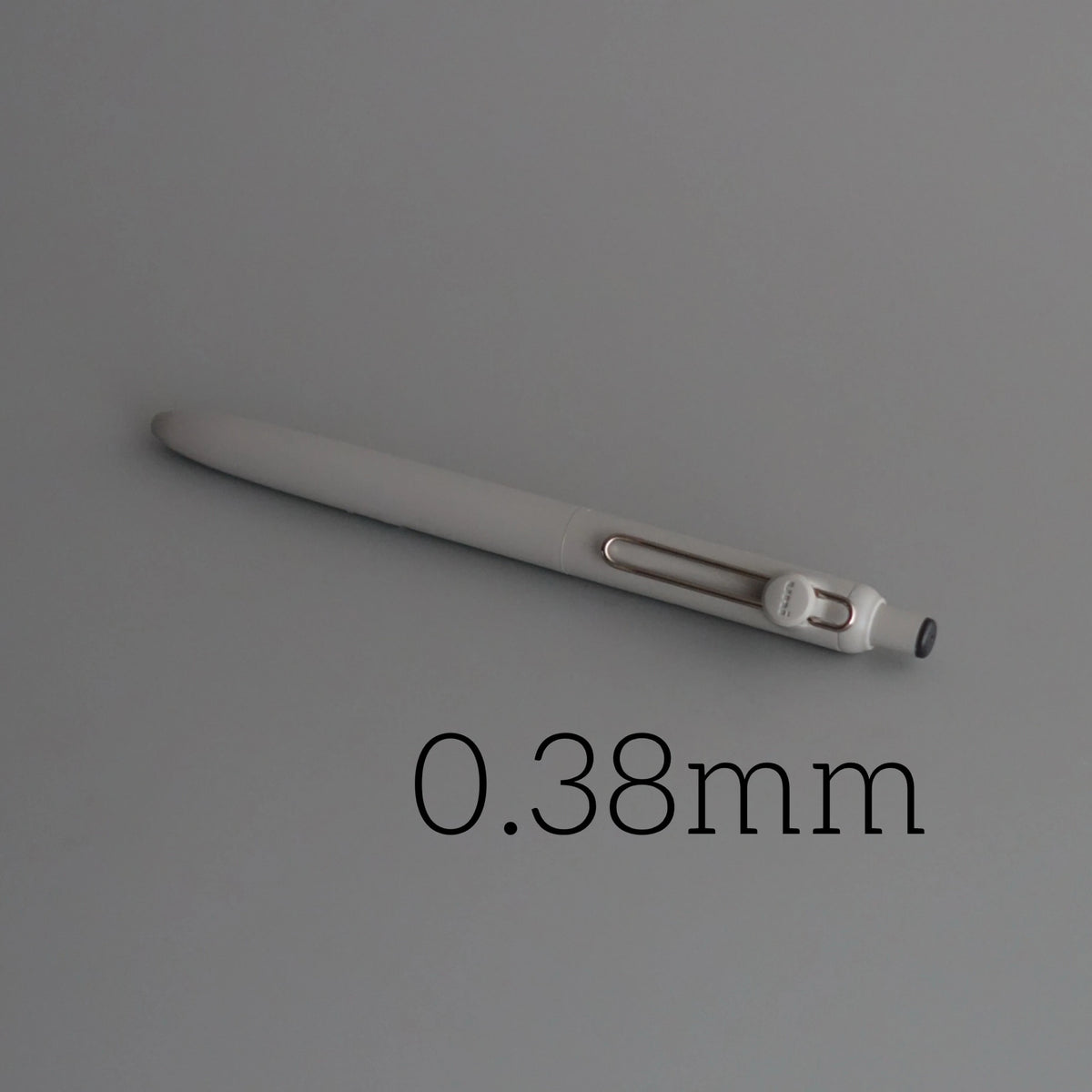 A close-up view of a silver precision gel pen with quick-drying ink, showing its size marked as 0.38mm.