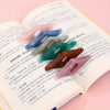 A collection of colorful resin thumb book stands displayed on the page of an open book.