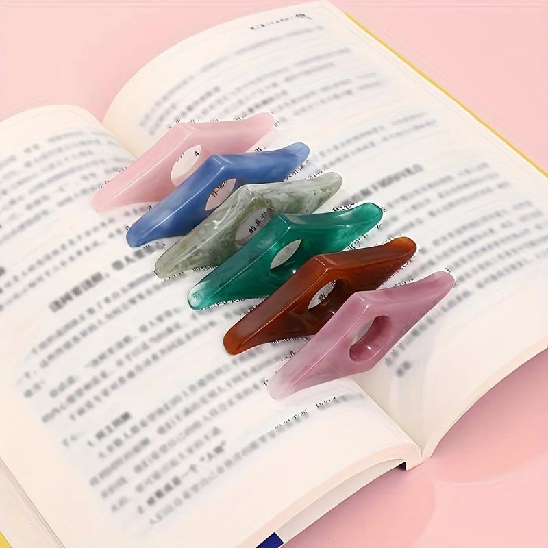 A collection of colorful resin thumb book stands displayed on the page of an open book.