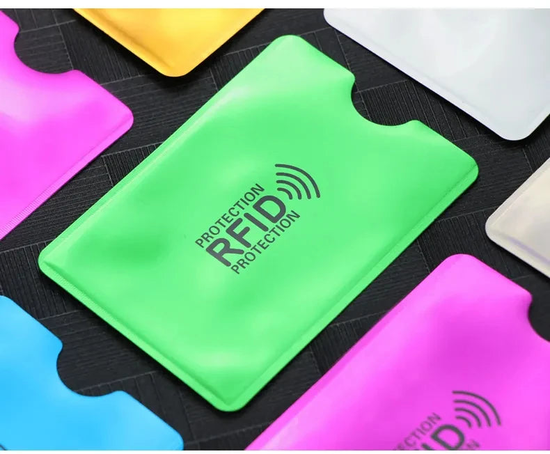 Collection de porte-cartes anti-RFID de couleurs vives, rose, jaune et vert, présentées sur une surface sombre.