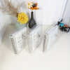 A set of clear plastic binders for goal-oriented savings, featuring labels like 25K, 5K, and 10K, displayed next to dried flo