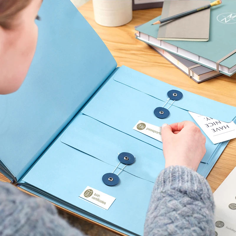 A person is opening a light blue expanding accordion document organizer file folder on a wooden table.