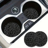 A set of two non-slip leather car cup holder coasters with leopard print texture shown in a silver holder.