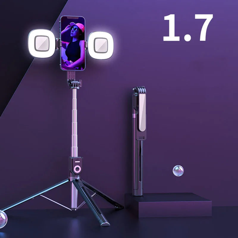 A silver extendable phone tripod with an LED ring light and mirror is displayed on a dark surface.