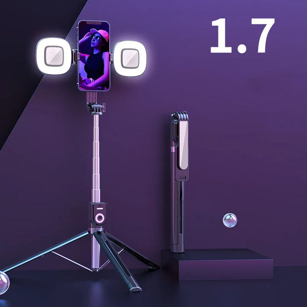 A silver extendable phone tripod with an LED ring light and mirror is displayed on a dark surface.