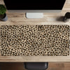 A leopard print XXL gaming mouse pad placed on a wooden desk in front of a computer monitor.