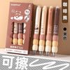 A set of four beige and pink erasable gel pens with soft grips are displayed in a brown box.