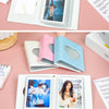 A set of pink and blue hollow photo card binders for Kpop albums displayed on a pink surface.