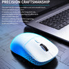 Souris sans fil bidirectionnelle blanche et bleue sur une surface sombre à côté d'un ordinateur portable.