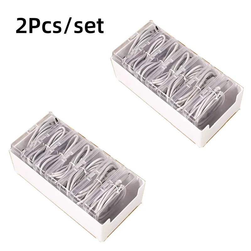 Two sets of cable organizer storage boxes containing multiple white cables for desk and travel use