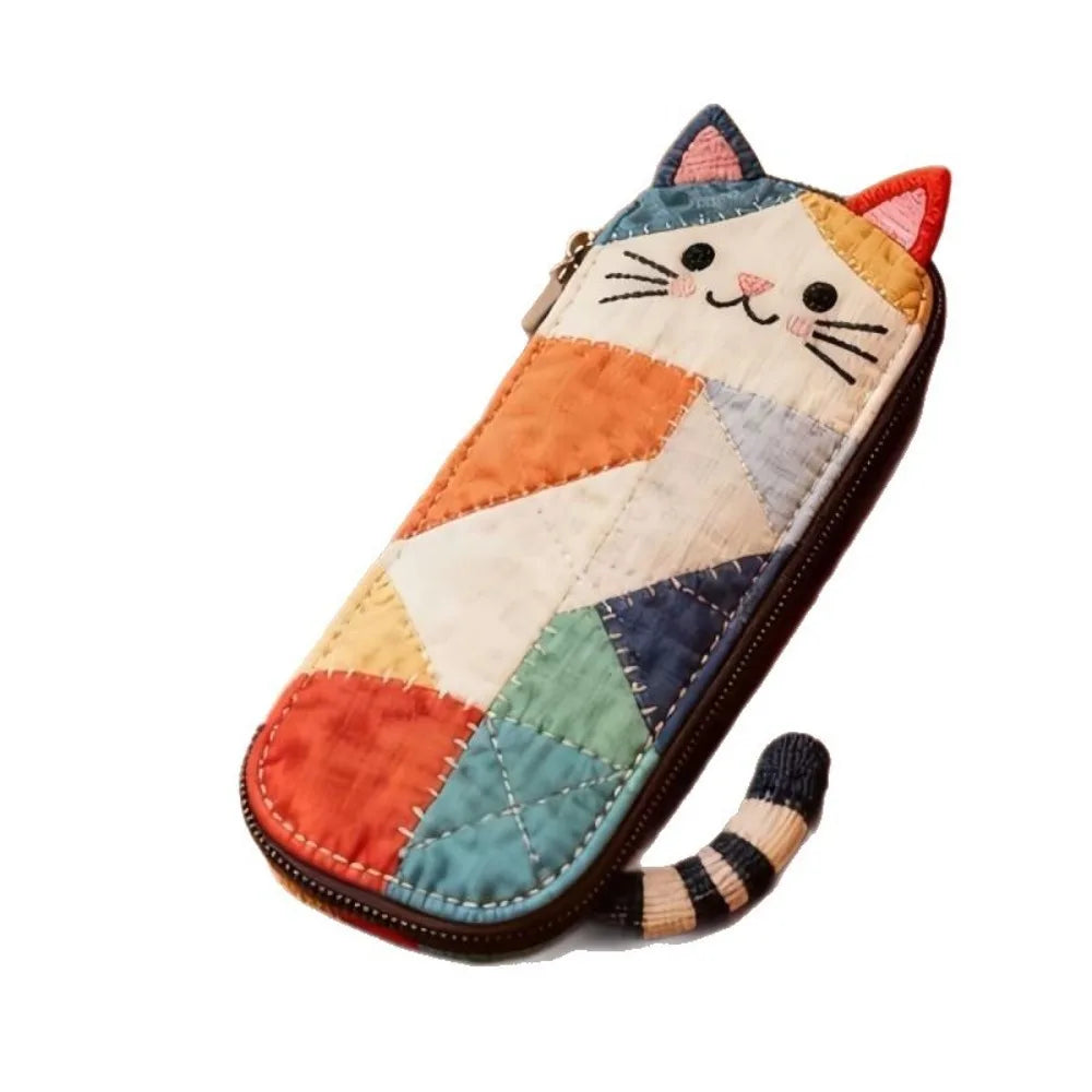 Patchwork cat face coin purse with zipper featuring multicolored fabric patches and a striped tail.