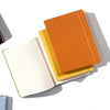 A stack of three A5 hardcover lined notebooks in orange, yellow, and orange.
