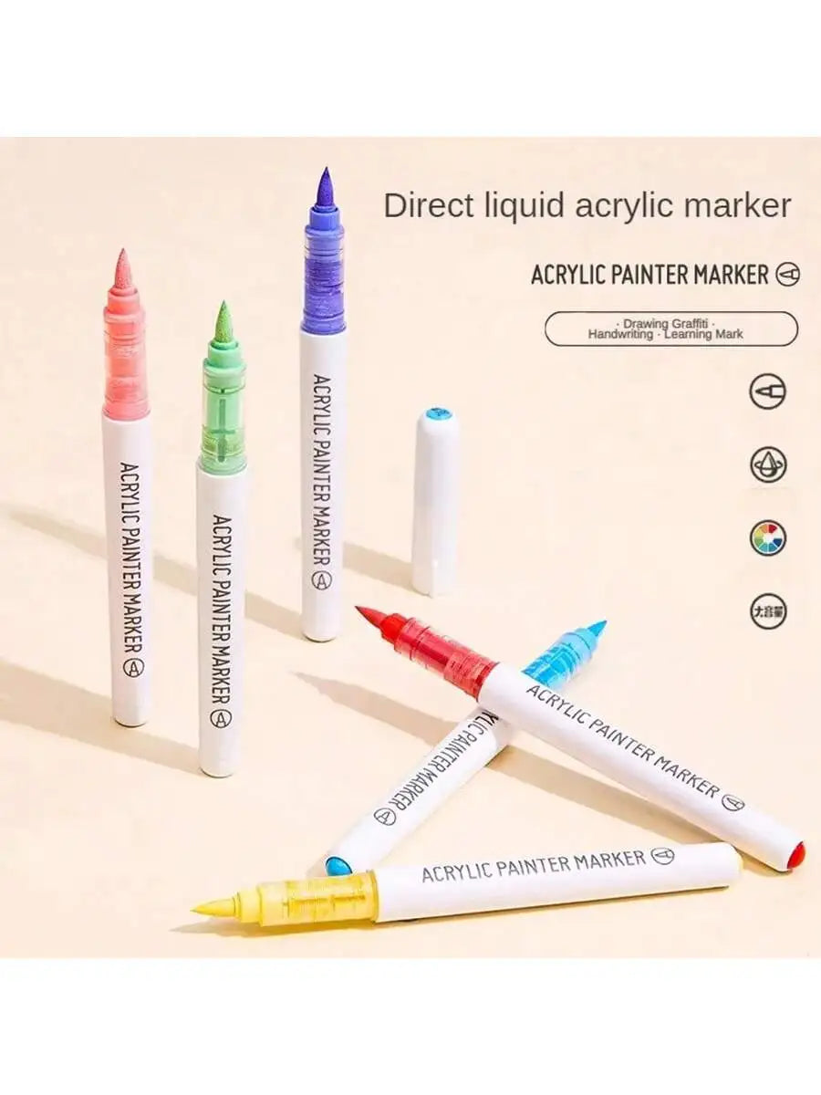 A set of direct liquid acrylic paint markers in various colors including pink, green, and purple, displayed on a light backgr