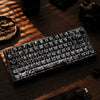 Nahaufnahme einer schwarzen mechanischen Tastatur mit Kohlenstoffmuster-Tastenkappen auf einer dunklen Holzoberfläche.