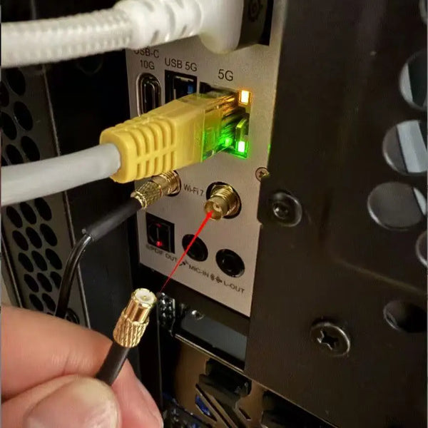 A hand is inserting a WiFi 7 antenna connector into a motherboard slot on a computer.