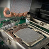 A hand is applying Arctic MX-6 high-performance thermal paste onto a CPU or component surface.