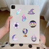 A white phone case decorated with purple magic witch stickers including a crystal, a witch hat, a moon, and a moon phase.