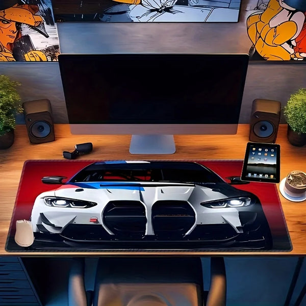 A large non-slip gaming mouse pad featuring a detailed racing car design on a wooden desk.