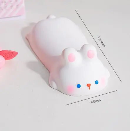 A white, cute, ergonomic wrist rest shaped like a rabbit is shown on a white surface.