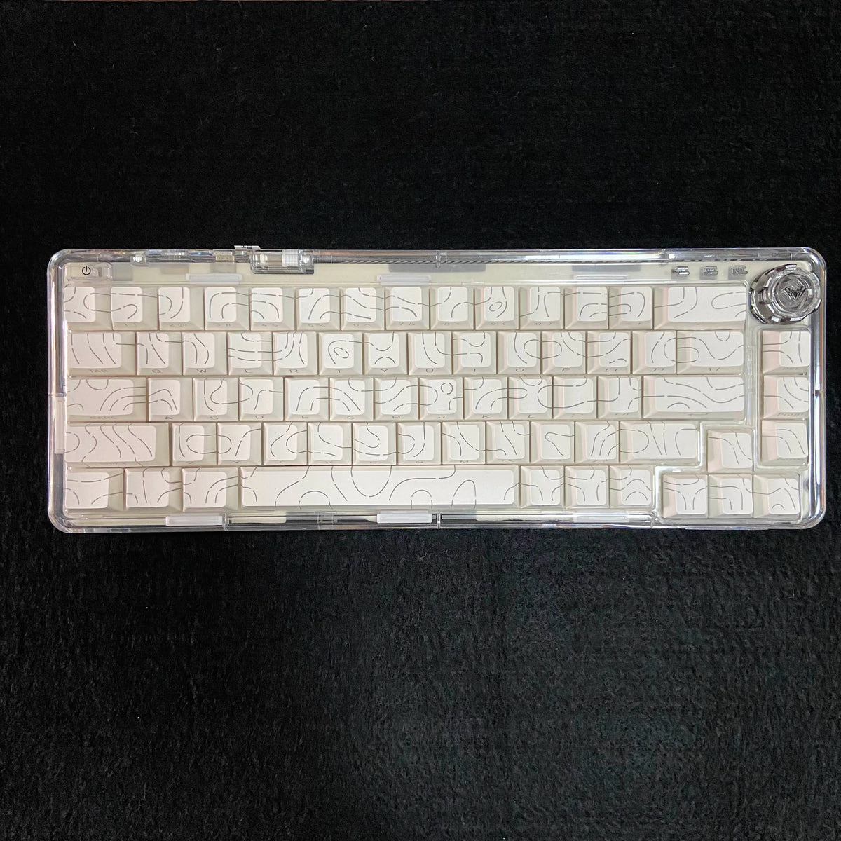 A close-up view of a clear plastic case containing side-lit cherry profile mechanical keycaps for custom keyboards.