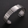 A stainless steel watch band with a textured metal link and a folding safety clasp is displayed on a dark background.