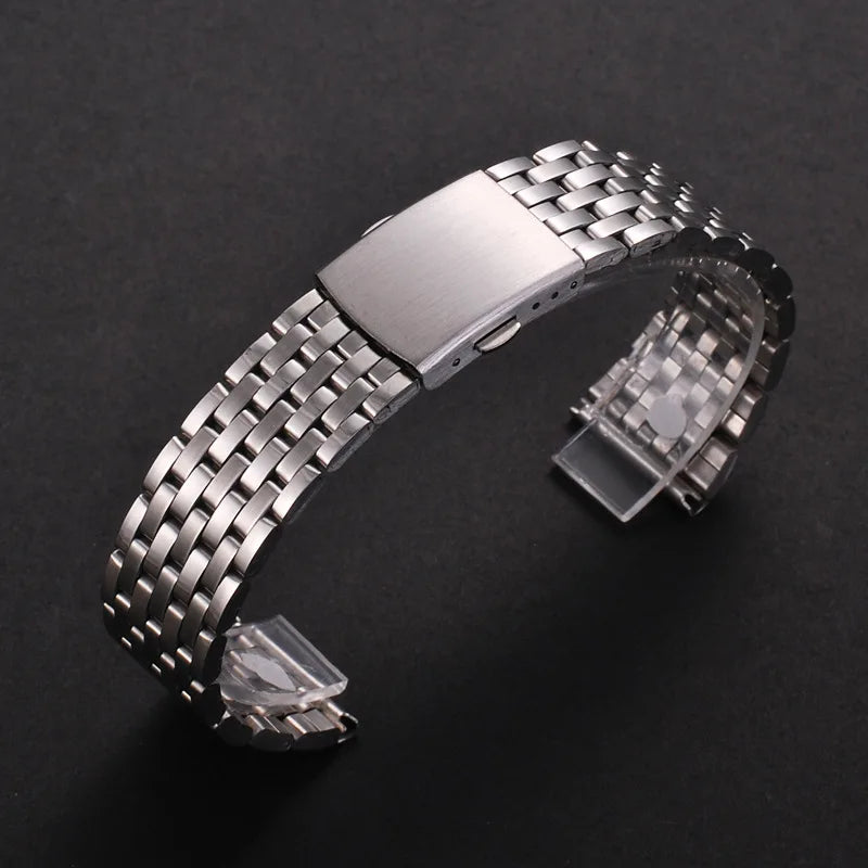 A stainless steel watch band with a textured metal link and a folding safety clasp is displayed on a dark background.