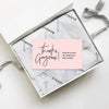 A square package of thank you cards with a pink message inside, resting on a white surface.
