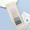 A sheet of transparent self-adhesive sticky notes in various pastel and gray shades is shown on a light blue background.