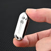 A hand holds a compact stainless steel pocket knife with a keychain attachment against a dark background.