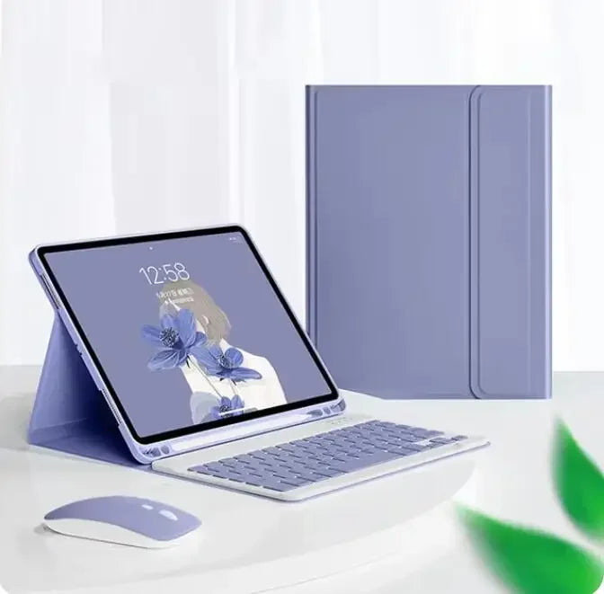 A silver magnetic keyboard case for an iPad Pro is shown next to a laptop and a purple folder.