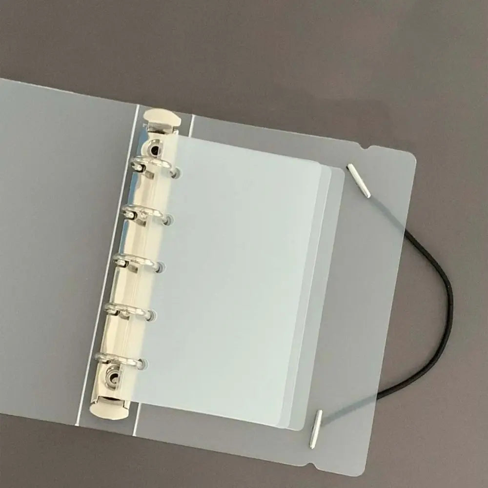 A transparent plastic divider page for a loose-leaf planner, showing the binding and pages.